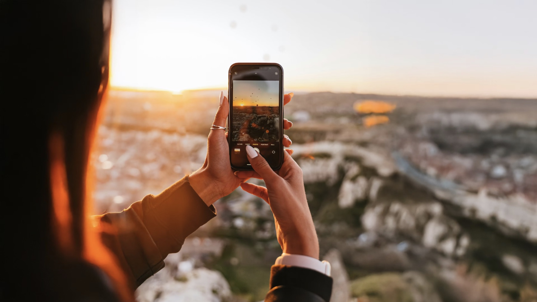 Someone framing a sunset on their phone camera